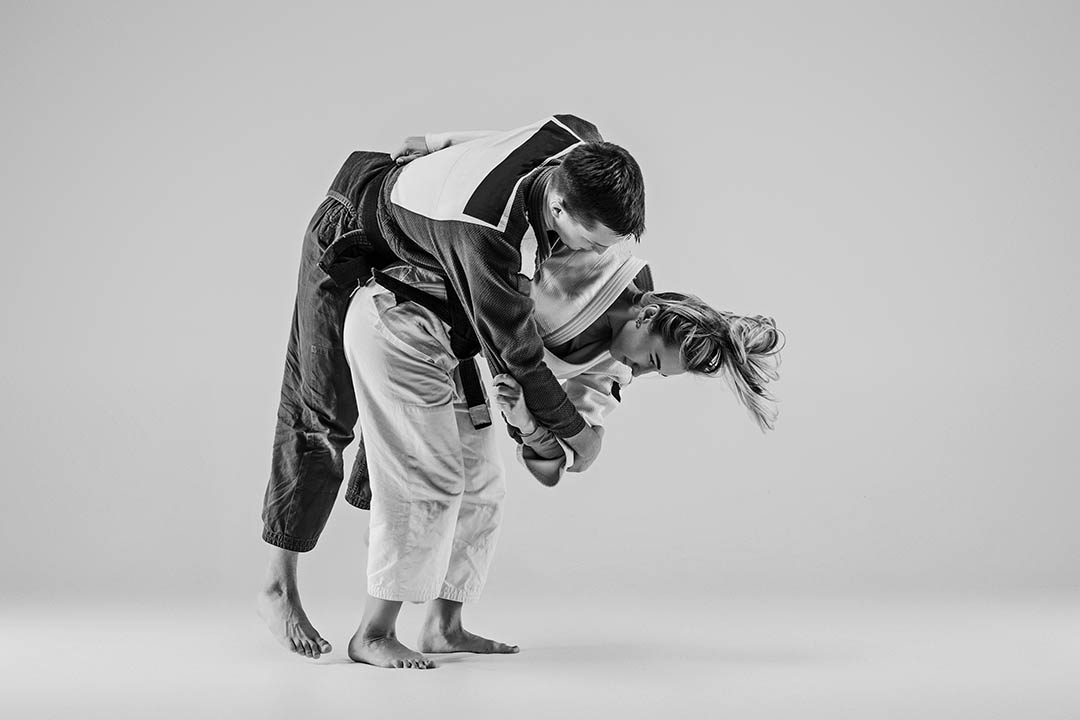 The two judokas fighters - man and woman - posing on gray studio background